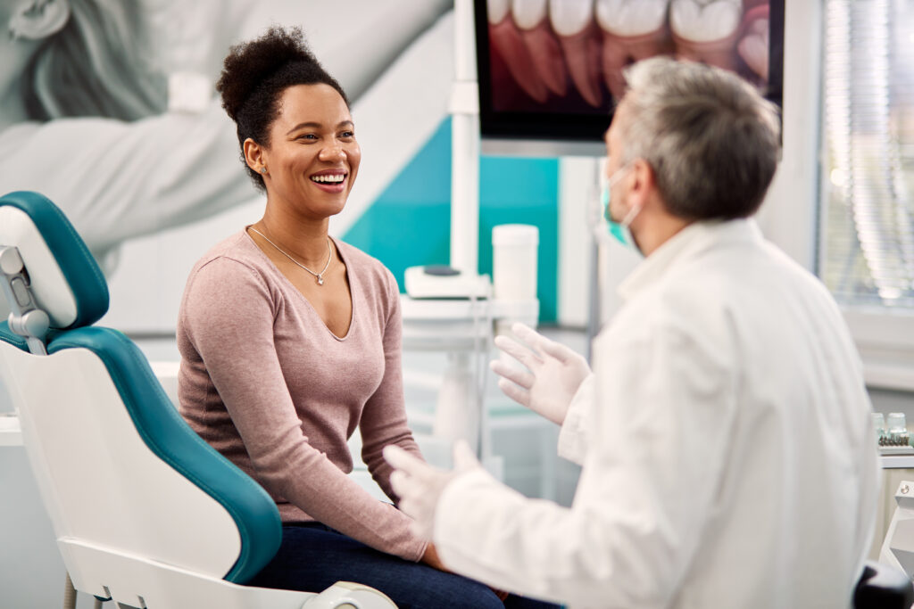 Happy Black woman talking to her dentist during appointment at dental clinic.